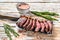 Grilled ramp cap steak on a meat cleaver. White wooden background. Top view