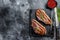 Grilled ramp cap steak on a stone chopping Board. Black background. Top view. Copy space