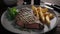 Grilled rib-eye steak, golden fries, and roasted herbs arranged on a white platter. Generative AI