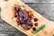 Grilled Ribeye Steak on bone with berry sauce, potatoes, tomatoes and rosemary on cutting board on wooden background