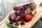 Grilled Ribeye Steak on bone with berry sauce, potatoes, tomatoes and rosemary on cutting board on wooden background