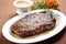 grilled ribeye on a white plate with peppercorn sauce