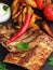 Grilled ribs with French fries and vegetables on the dark background. Shallow depth of field. Vertical orientation