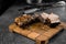 Grilled ribs slicing on a wooden plate on a gray background. Barbecue decoration.