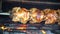 Grilled Rotisserie Chicken - Roasted chickens on spit grilled over wood fire on big bbq barbecue