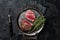 Grilled Rump sirloin steak sliced on a tray with herbs. Black background. Top view