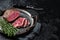 Grilled Rump sirloin steak sliced on a tray with herbs. Black background. Top view. Copy space