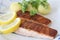 Grilled salmon fish filets on a plate with potatoes, parsley and slices of lemon. Close up stock photo with white back