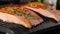 Grilled salmon fish with rosemary on electric grill, opening the cover. Food preparation, healthy diet concept, closeup