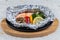 Grilled Salmon in a Foil Pack with broccoli, bell pepper, mushroom and slice lemon served in hot plate on wooden plate on washi.