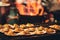 Grilled scallops sold at a street market stall with a pan covered with flames on the background. Chinatown, Bangkok, Thailand