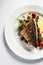 Grilled sea bass with fried tomatoes, served with potatoes. Fish dish top view, light background, copy space