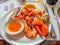 Grilled seafood, shrimps, lobsters, crabs, prawns, served with tasty sour spicy sauce on white dish