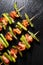 Grilled skewers with asparagus and bacon on black stone background