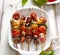 Grilled skewers of vegetables and meat in a herb marinade on white plate