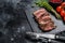 Grilled sliced flank steak with seasonings and spices. Black background. Top view. Copy space