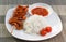 Grilled snake on skewer with chili sauce and rice on white plate on mat