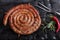 Grilled spiral sausages on a black background of charcoal