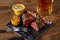 Grilled steak with corn with mushrooms sauce on cutting board and mug of beer on wooden table