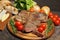 Grilled T bone steak with rosemary, tomatoes, corn, onions and