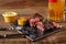 Grilled tenderloin Steak roastbeef and mushrooms sauce on black cutting board and glass of beer on wooden background