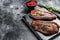 Grilled top sirloin cap or picanha steak on a stone chopping Board. Black background. Top view. Copy space