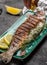 Grilled trout served with lemon. chef sprinkles lemon juice on grilled trout, Food recipe background. Close up