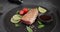 Grilled tuna steak on a black stone serving board with teriyaki soy sauce and pieces of lime