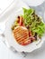 Grilled Turkey Breast with tomatoes and various olives. Bright wooden background.
