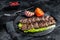 Grilled Urfa kebab with tomato, salad and onion. Black background. Top view