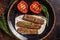 Grilled Urfa shish kebab on a plate with tomato. Dark background. top view