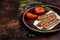 Grilled Urfa shish kebab on a plate with tomato. Dark background. top view. Copy space