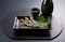 Grilled urume sardines on a black table. A side dish of sake