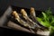 Grilled urume sardines on a black table. A side dish of sake