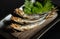 Grilled urume sardines on a black table. A side dish of sake