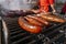 Grilling different kinds of sausages, dry and fresh meat on an open barbeque