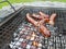 Grilling sausages on the grill. Frying food on charcoal and on fire. Fatty food. Calories and energy for muscles. Picnic on the st