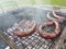 Grilling sausages on the grill. Frying food on charcoal and on fire. Fatty food. Calories and energy for muscles. Picnic on the st