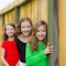 Grils group in a row smiling in a wooden fence