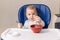 The grimy infant or toddler tries to eat independently. Baby-led weaning. Little child eats himself with a spoon.