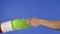 Grinchs green haired hand hold a gift box and a mans hand takes it away on a blue isolated background. Gift