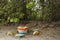 A grinding table with stone grinder made out of brightly painted pieces of concrete and rocks by the beach and tro