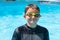 Grinning boy in swim shirt and goggles at pool