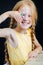 Grinning ginger girl with long braids sitting behind a table, showing crayons