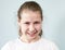 The grinning pre-teen girl looks at the camera, grey background, emotions series