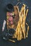 Grissini bread sticks, sausage, black olives, wine over dark background