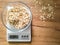 Grits weighing in glass bowl on the kitchen scales on wooden table.