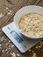 Grits in a white bowl on the kitchen scales on wooden background