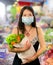 Groceries shooping during covid-19 virus quarantine - young beautiful and positive Asian Chinese woman in mask carrying vegetables