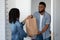 Grocery Delivery. Smiling Black Courier Delivering Order To Young Woman`s Home